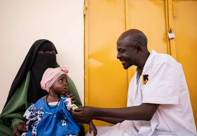 17-month-old Safia has her upper arm measured using tape to diagnose malnutrition. 